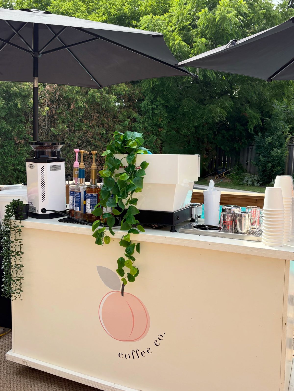 Peach Coffee Co. mobile coffee bar set up under umbrellas at an outdoor event